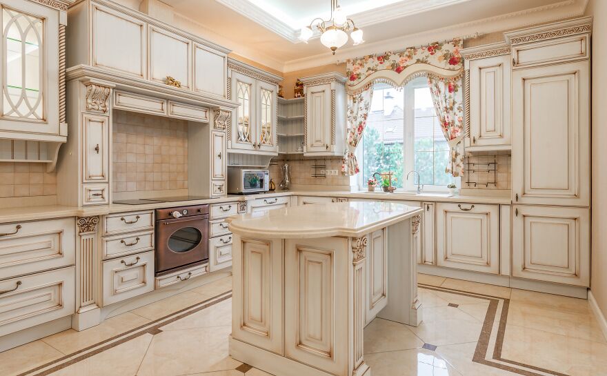 Vintage style kitchen featuring modern and stylish kitchen cabinets with intricate detailing and a central island.