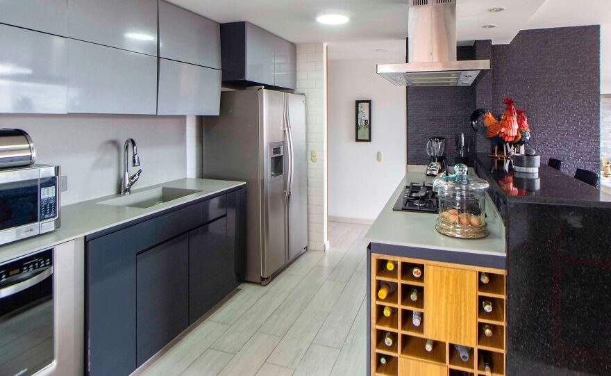 Black and grey kitchen featuring modern and stylish kitchen cabinets with a built-in wooden wine bottle storage cabinet.