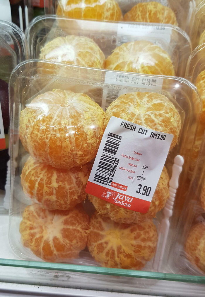 Clear plastic packaging fails by containing peeled oranges stacked tightly with a label showing price and product details.