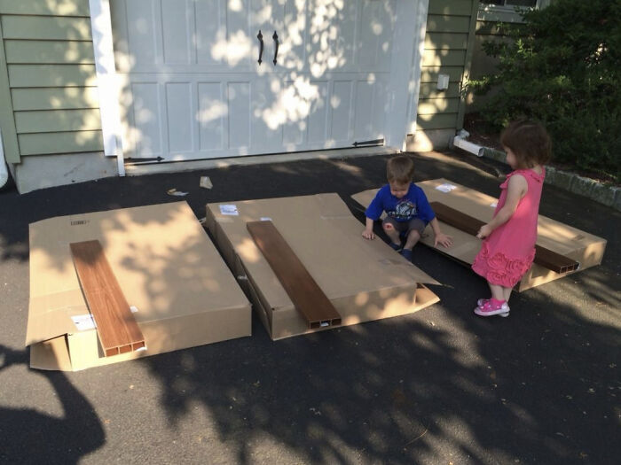 Two children playing on large cardboard boxes on a driveway illustrating facepalm-worthy packaging fails.