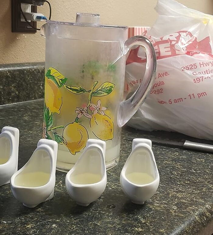 Quirky gifts: lemonade pitcher and mini urinal cups on a kitchen counter.