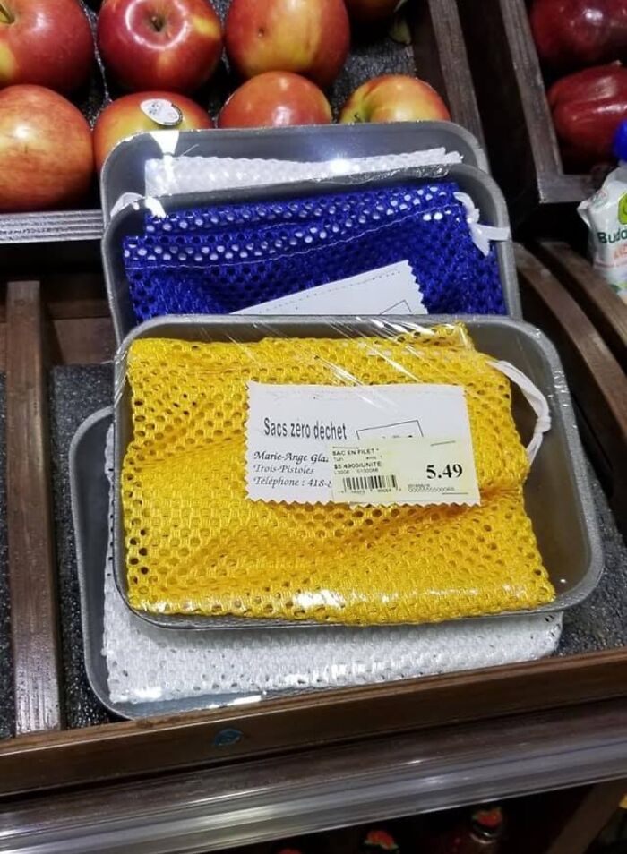 Reusable mesh bags wrapped in plastic packaging displayed near apples, showing a clear packaging fail example.