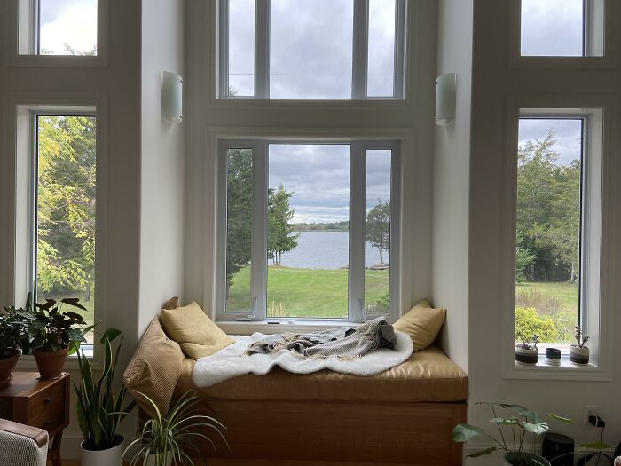 Cozy window seat ideas featuring a cushioned nook with pillows and blanket overlooking a scenic lake view.
