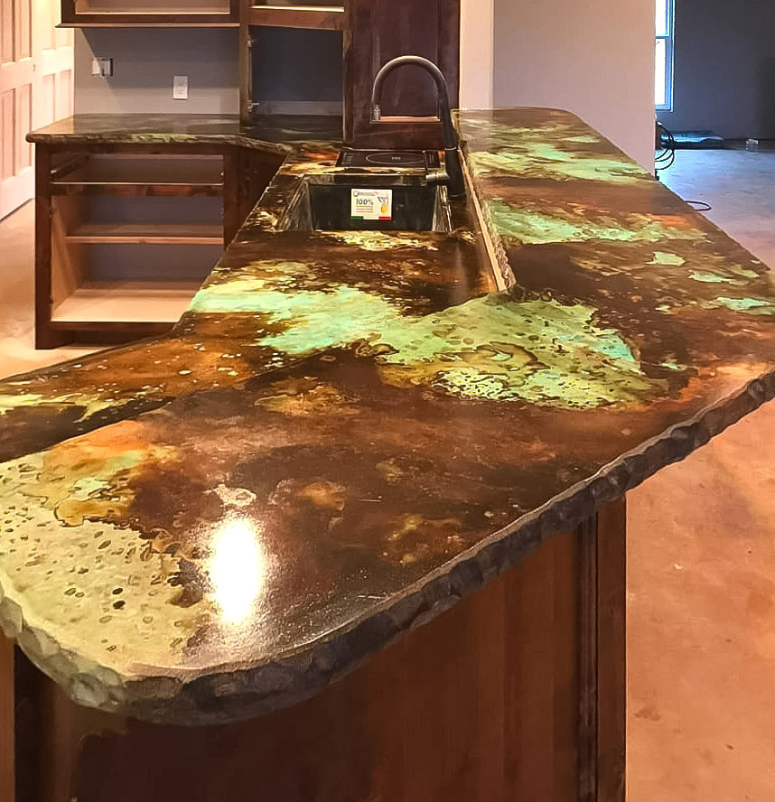 Acid-etched concrete countertop with green and brown patina finish showcasing unique texture and design in kitchen setting.