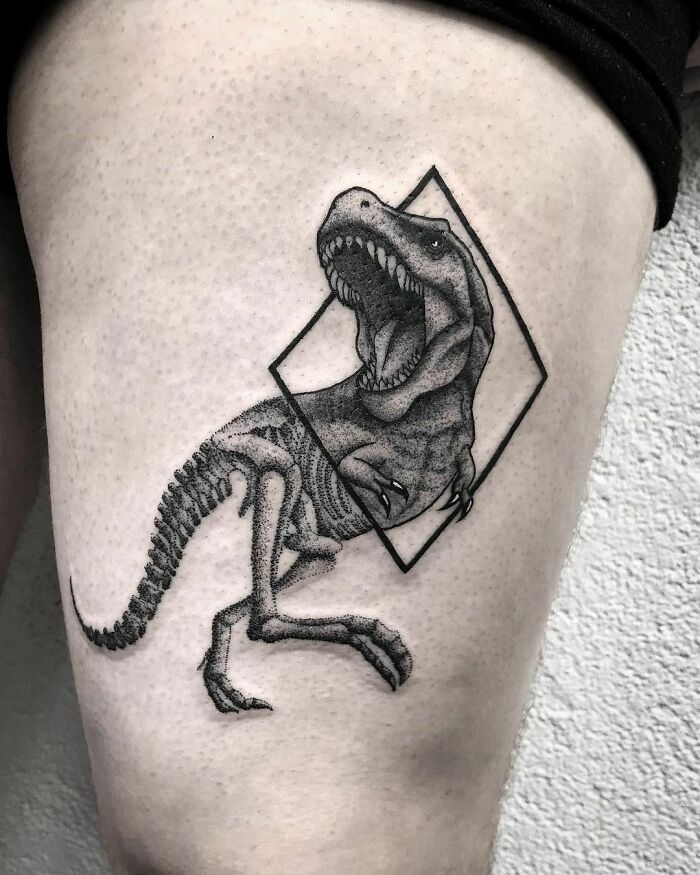Dinosaur tattoo on a thigh featuring a roaring T-Rex in a geometric design, executed with intricate detail.