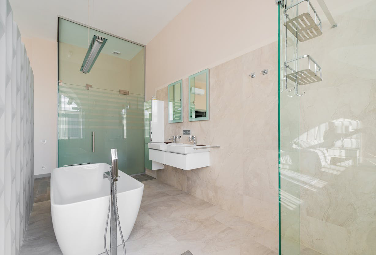 Tiled bathroom with light grayish pink painted walls, white tub and shower