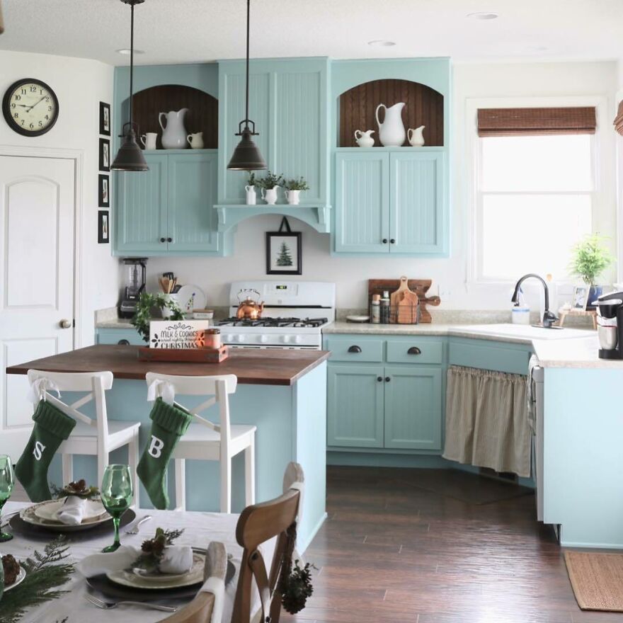 Kitchen with modern turquoise kitchen cabinets featuring a wooden countertop and white appliances in a bright space.