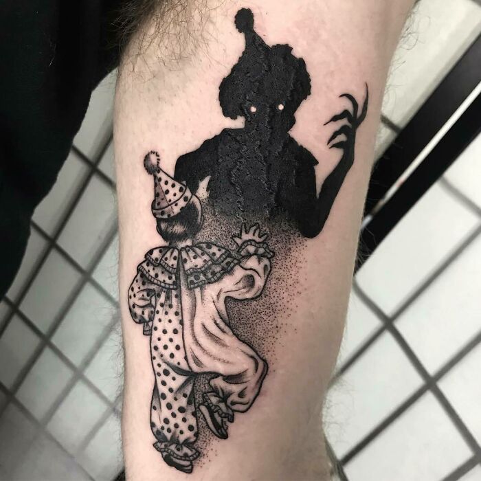 3D tattoo of a playful clown and menacing shadow on skin, showcasing intricate artistry.
