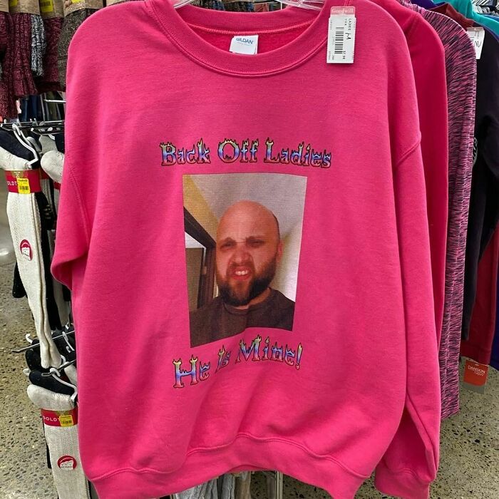 Bright pink sweatshirt with a humorous printed photo and text, one of the weird items donated to thrift stores.