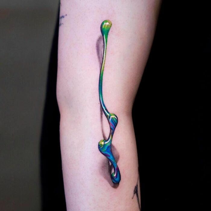A vibrant 3D tattoo design with colorful swirls on an arm, creating a realistic popping effect.