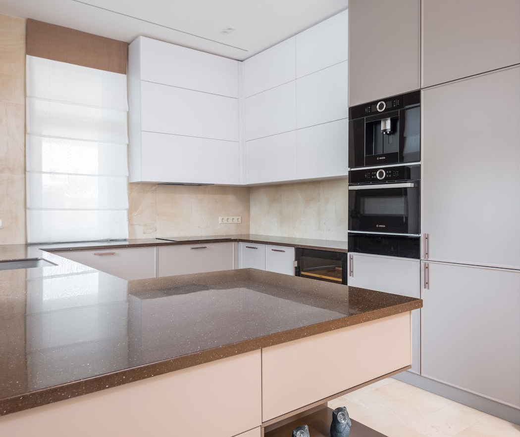 Modern kitchen featuring polished brown concrete countertops paired with sleek light gray cabinetry and built-in appliances.