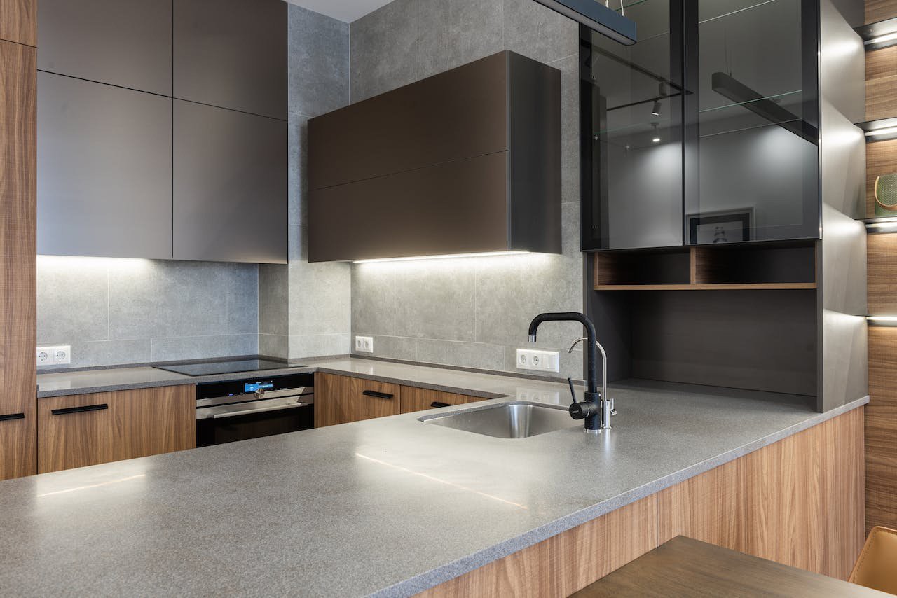 Modern kitchen featuring durable concrete countertops paired with sleek wooden cabinets and integrated lighting.