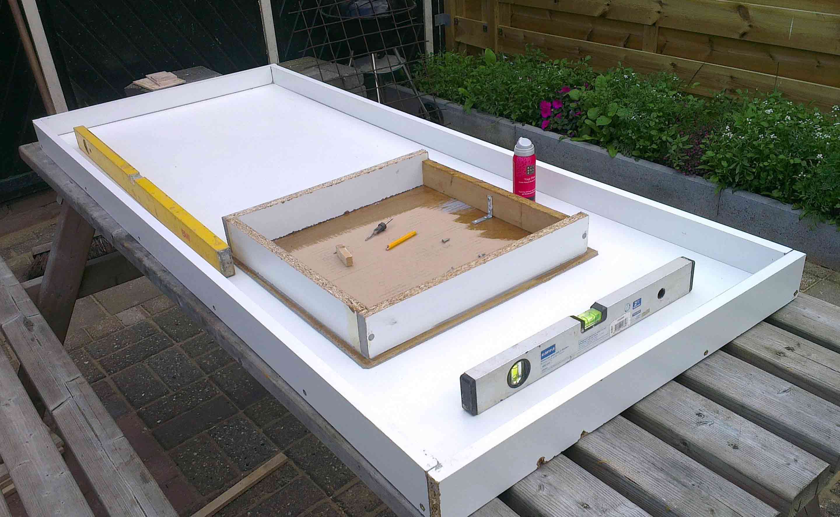 DIY concrete countertop mold setup with tools and levels on a wooden workbench, preparing for concrete pouring.
