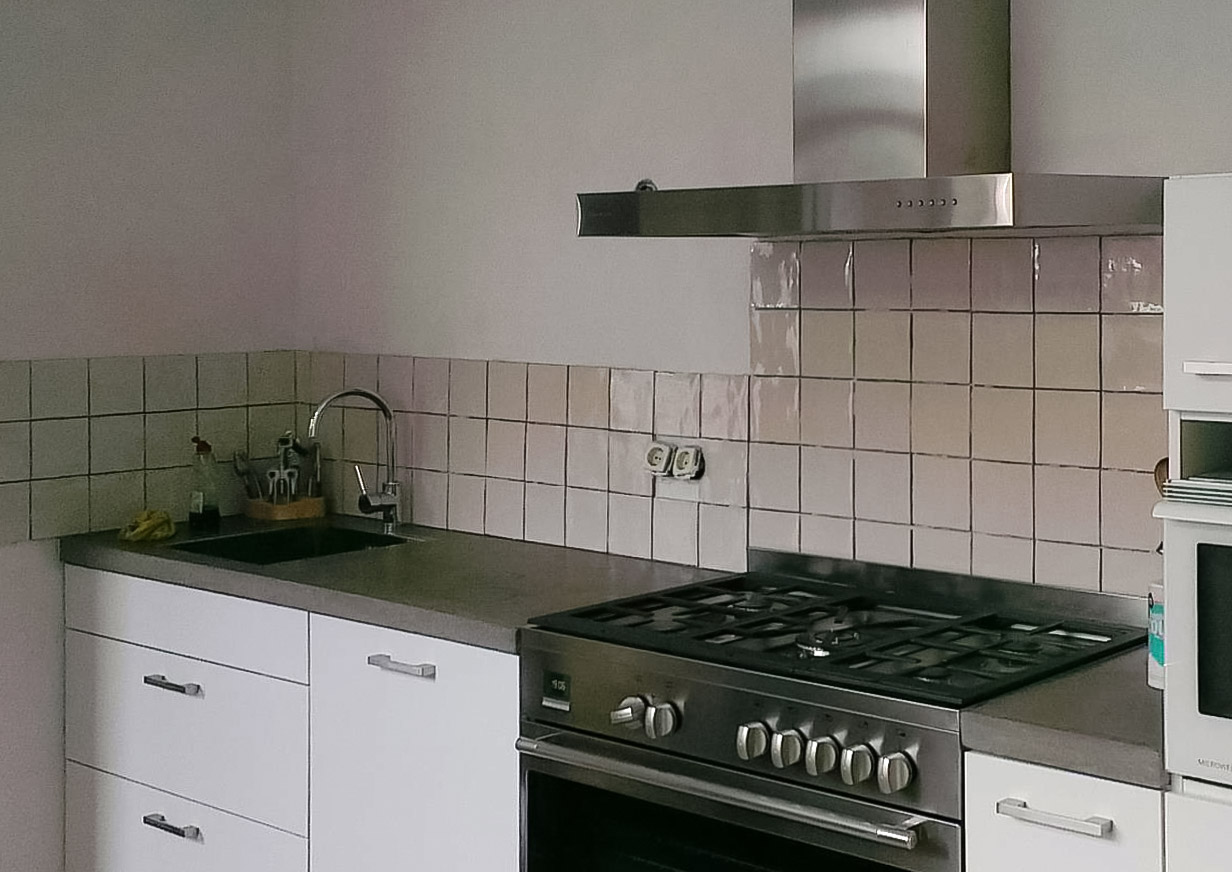 Modern kitchen featuring a DIY concrete countertop with white cabinets and stainless steel stove and hood.