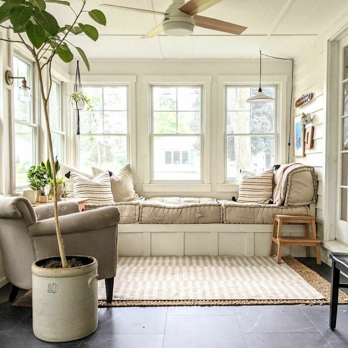 Farm style bright window seat with cozy cushions and striped pillows creating a warm and inviting window nook space.