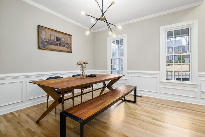 Dining room featuring wainscoting panels, a wooden table with bench seating, and a painting on the wall.
