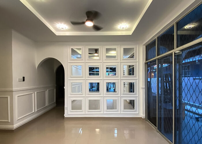 Interior showcasing mirrored wainscoting panels with a modern ceiling fan and sleek tiled flooring in a home.