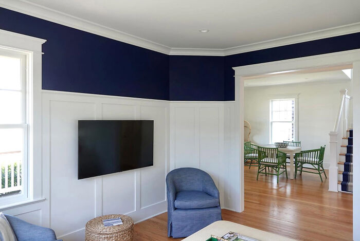 Beach house living room with dark navy walls and white wainscoting panels showcasing classic home decor.
