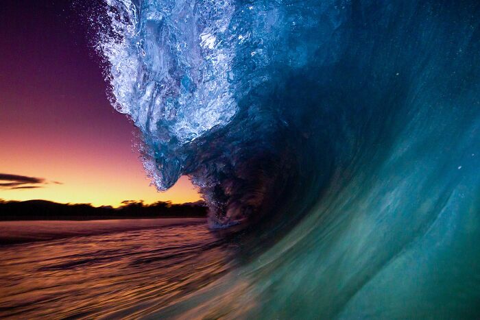 Close-up of a large ocean wave curling at sunset, showcasing stunning nature photography from 2023 awards.