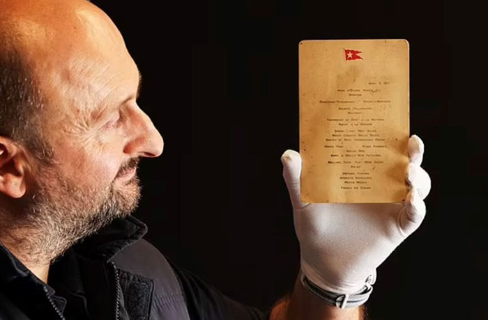 Man holding a recovered Titanic first-class menu, revealing what rich people ate aboard.
