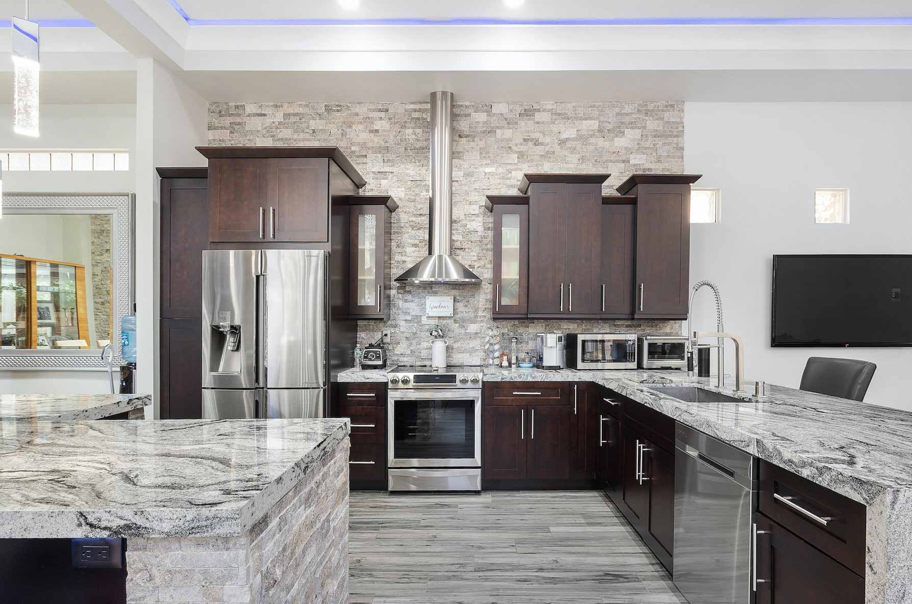 Modern kitchen with dark brown wooden cabinets and stained concrete countertops featuring stainless steel appliances.