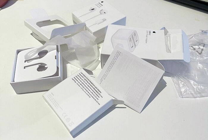 Packaging fail showing multiple opened and damaged white electronic accessory boxes scattered on a white surface.