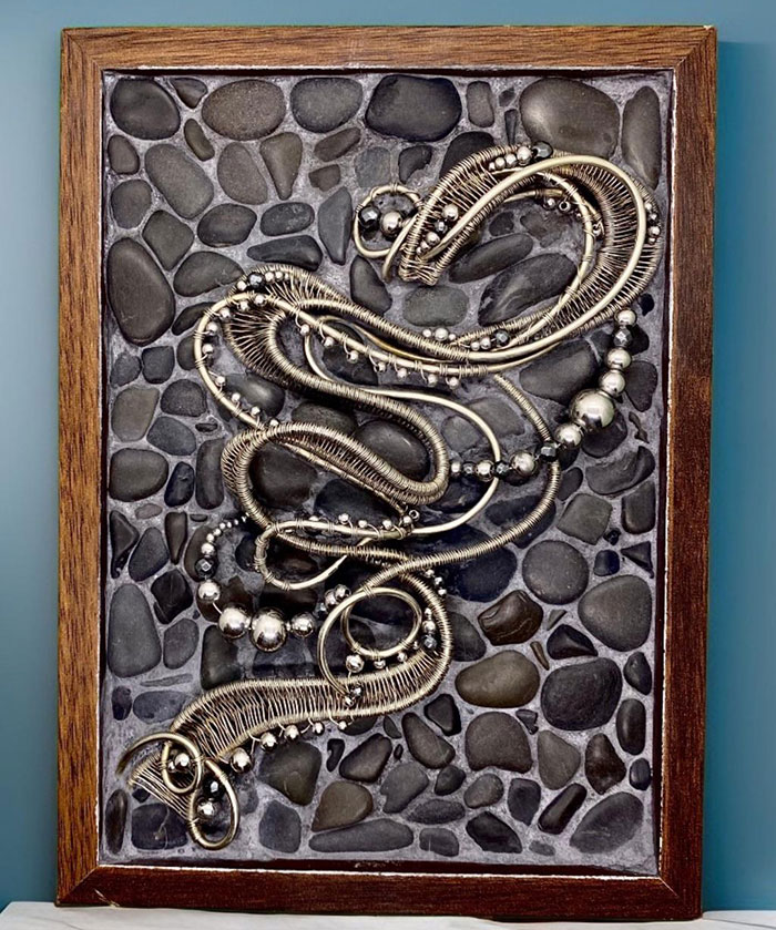 Framed vintage jewelry art displayed on a textured stone background, showcasing creative wall art ideas for a stylish space.