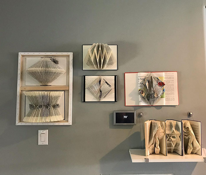 Book hung wall art displaying creative folded pages arranged on a gray wall for stylish space decoration.