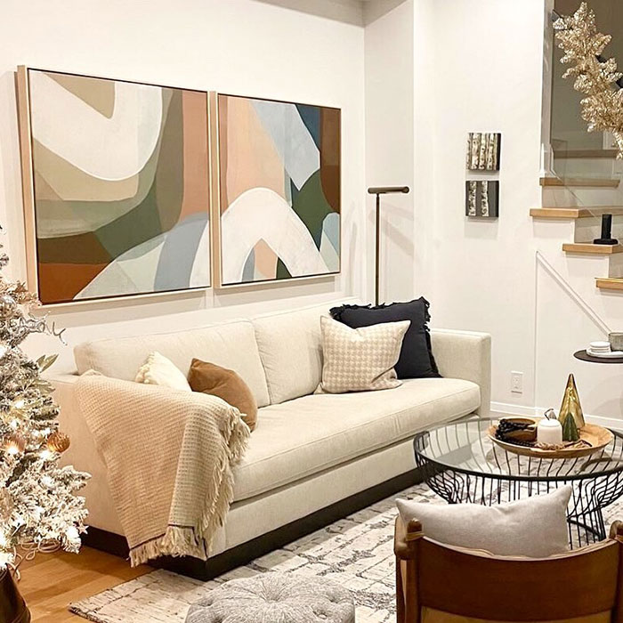 Two abstract art pieces above a beige sofa with pillows, showcasing easy and creative wall art ideas for a stylish space.
