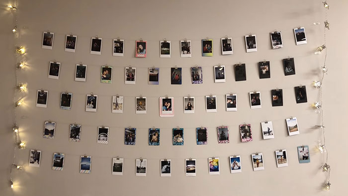 Polaroids displayed on string lights against a wall, showcasing creative wall art ideas for a stylish space.