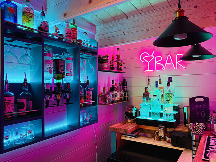 Neon sign wall art illuminating a stylish home bar with colorful lighting and creative decor elements.