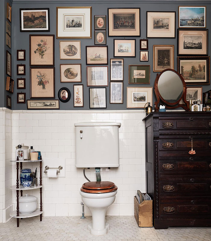 White bathroom with multiple framed paintings on a wall showcasing easy and creative wall art ideas for a stylish space