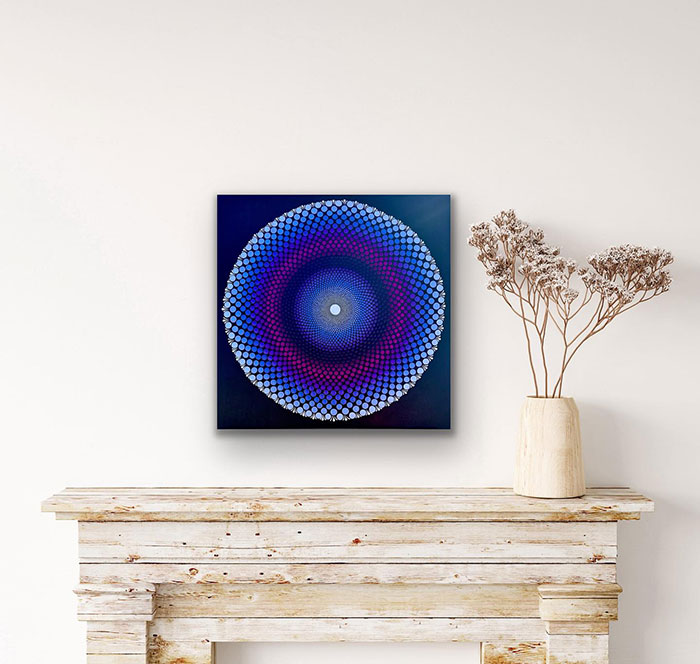 Mandala art wall painting featuring vibrant blue and purple patterns displayed above a rustic wooden mantel.