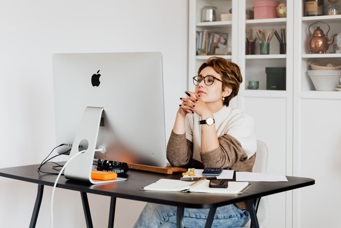 Woman sitting on computer with crossed hands 