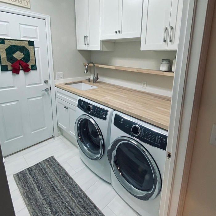 Laundry room with front-load washer and dryer featuring a butcher block countertop for classic charm and durability. Laundry room with front-load washer and dryer featuring a butcher block countertop for classic charm and durability.
