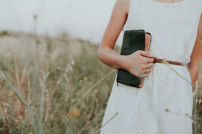 Woman in a white dress holding a book in a field, symbolizing moments that made people think a divorce was coming.