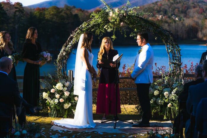 Bride and groom standing under floral arch at outdoor wedding, capturing moments that hint at possible divorce signs.