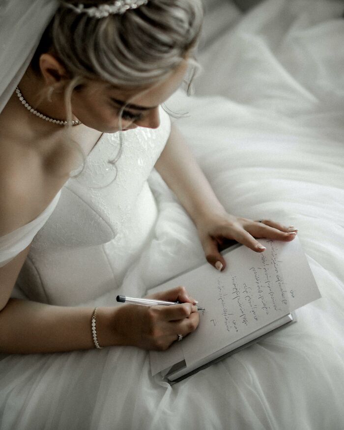 Bride in wedding dress writing in a notebook, capturing moments that made people think a divorce was coming.