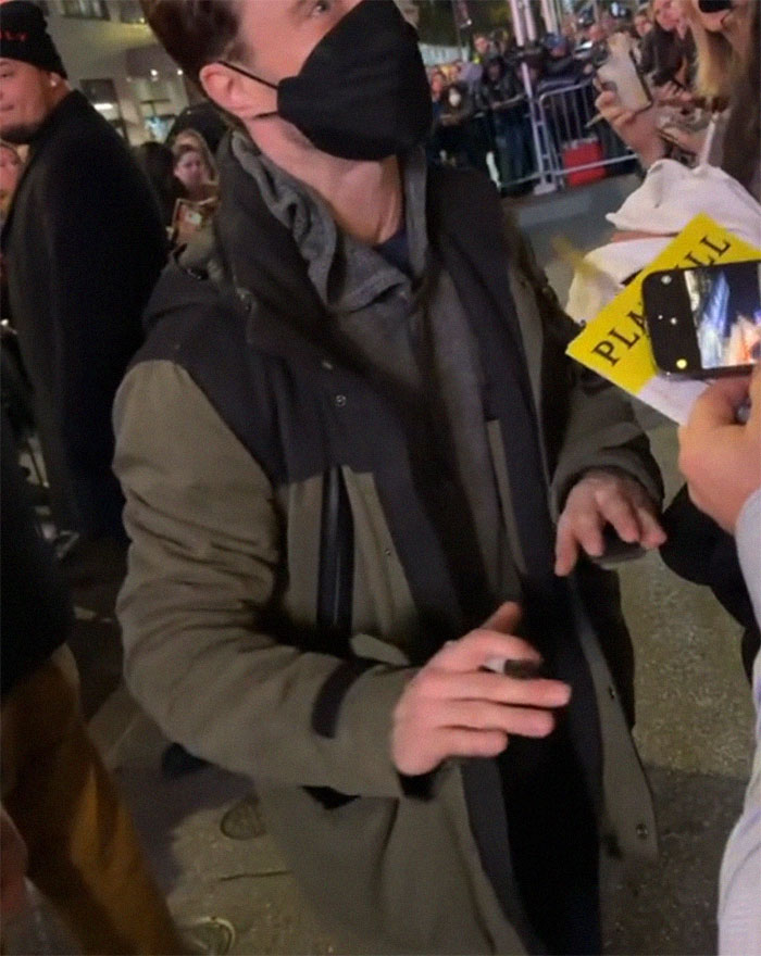 Daniel Radcliffe interacts with fans, holding a pen amidst a crowd, at night. Daniel Radcliffe interacts with fans, holding a pen amidst a crowd, at night.