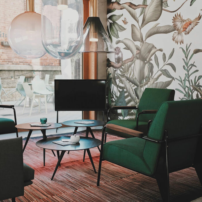 Dining room with colorful botanical wallpaper and green chairs creating inspiring dining room ideas for family gatherings and parties.