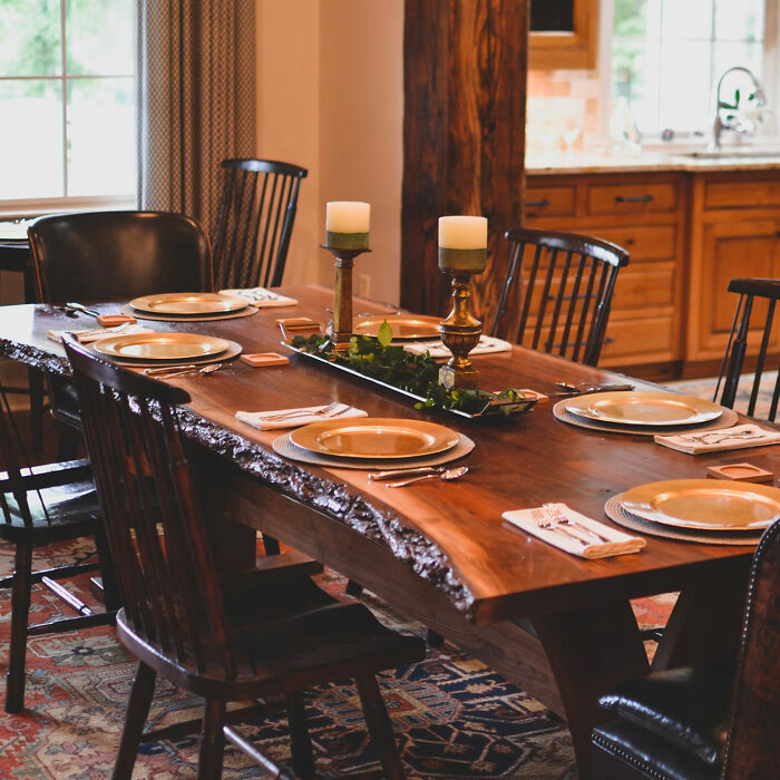 Rustic wooden dining table and chairs set with candles, plates, and napkins for family gatherings and parties.