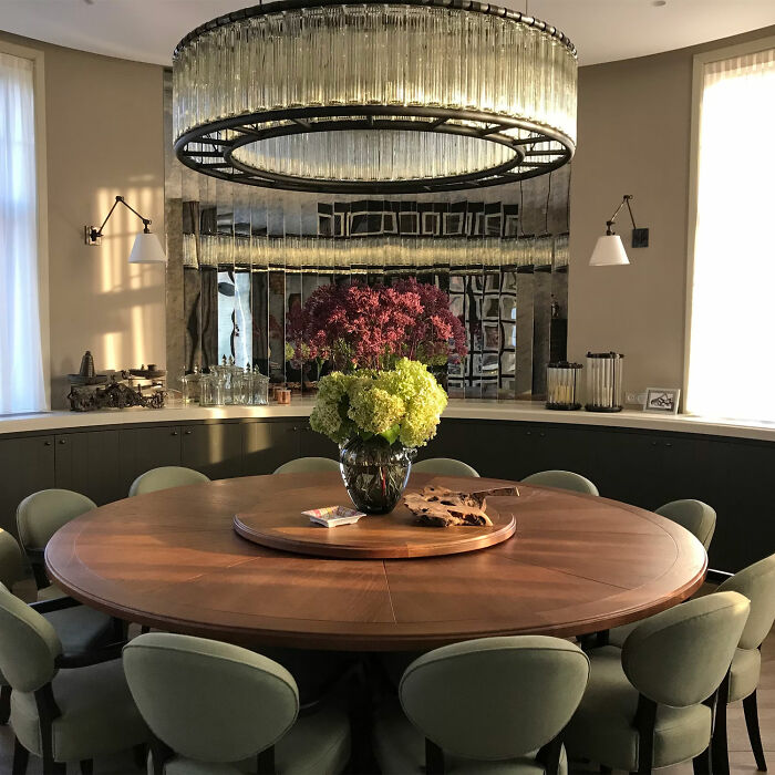 Elegant dining room with wooden table, green chairs, banquette seating, and a large chandelier for family gatherings.