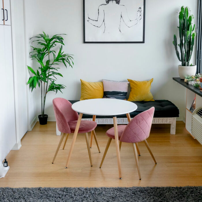 Modern dining room with white table and pink chairs, styled to inspire family gatherings and party decor ideas.