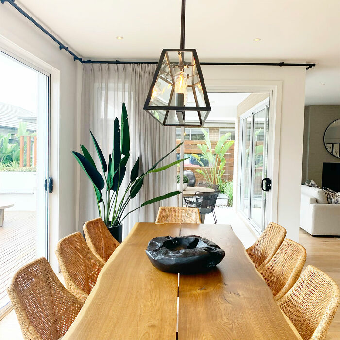 Dining room with wooden table, wicker chairs, and lantern-style lighting creating a warm family gathering space.