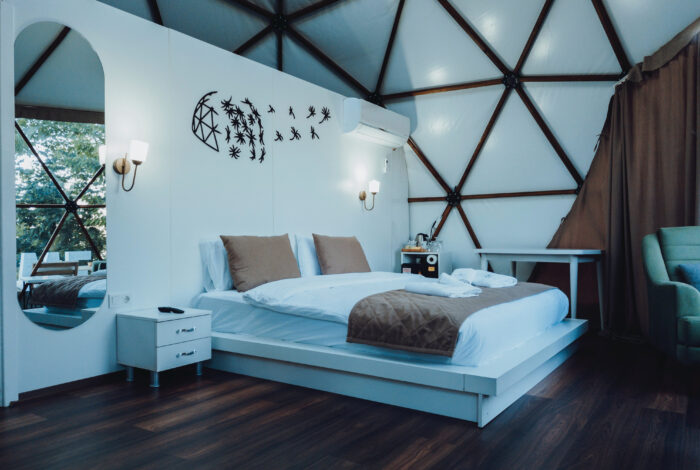 Big bed with white and brown linens near the wall with sticks