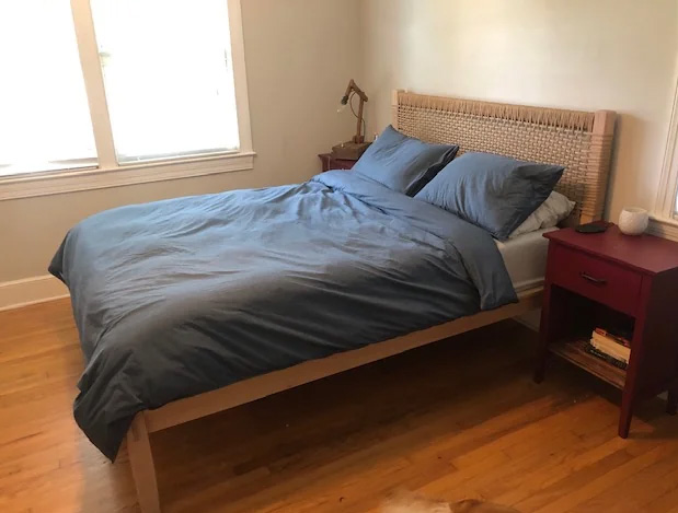 Bed with grey linens and woven cane headboard