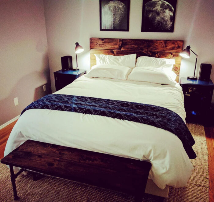 Bed with white linen and wooden bench nearby