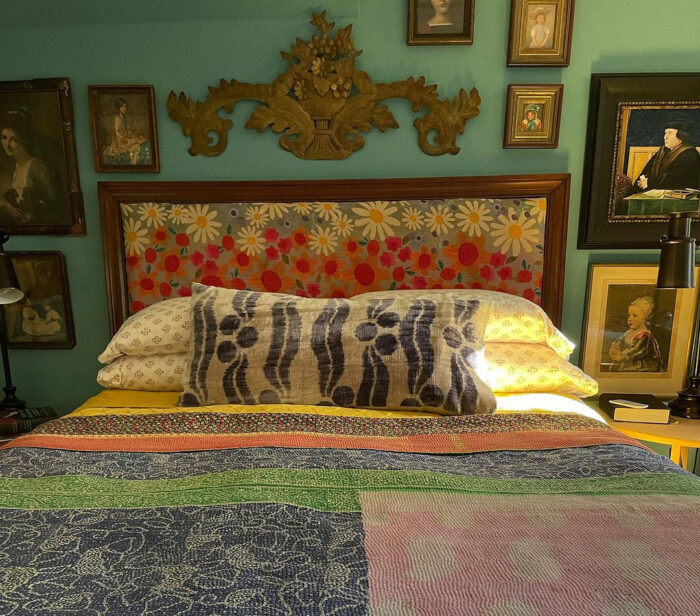 Bright cover on the bed near the wall with pictures