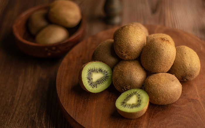 Fresh kiwi fruit sliced open on a wooden board, highlighting its texture and color.