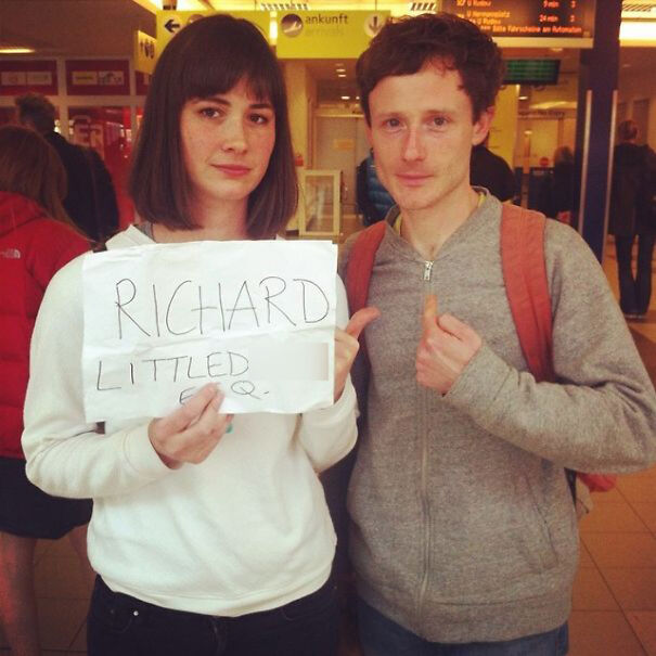 Two people holding a humorous airport pickup sign that says "Richard."